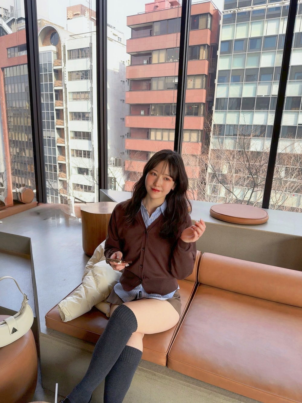 ブラウン系のカーディガン/ボレロ、ブラック系のローファー、ホワイト系のハンドバッグを着用したレディースの冬コーディネートの2枚目の写真