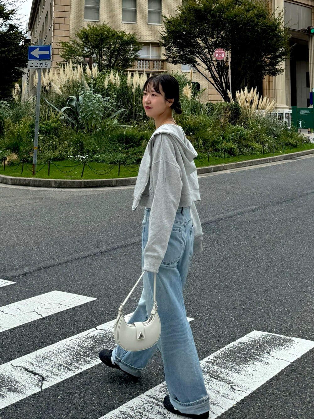 グレー系のキャミソール、ブルー系のデニムパンツ、ブラック系のスニーカーを着用したレディースの秋コーディネートの3枚目の写真