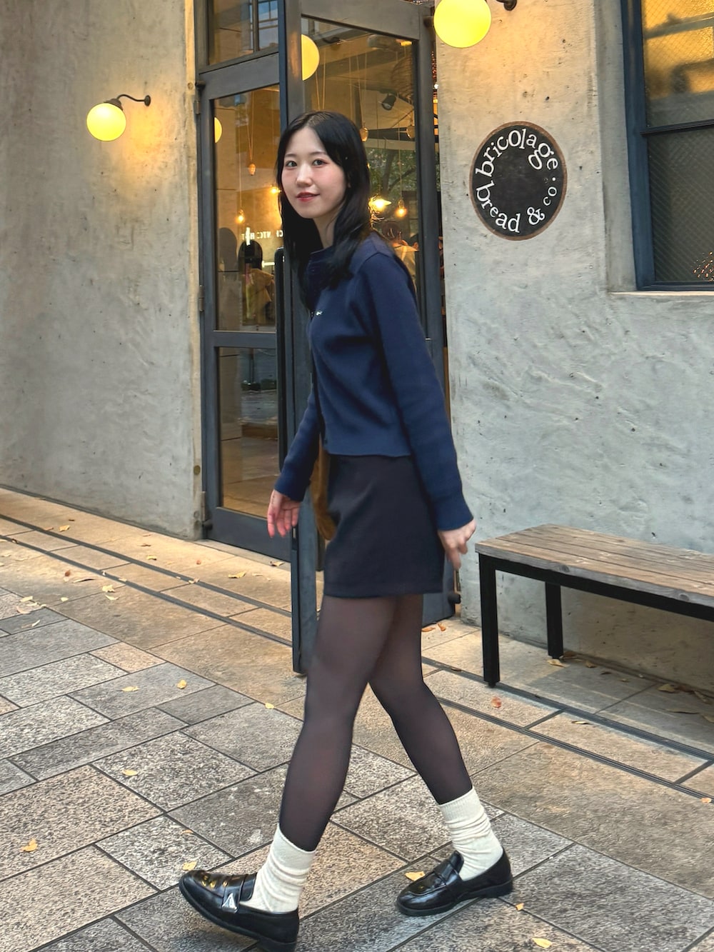 ブルー系のカーディガン/ボレロ、ブラック系のスラックス、ブラック系のローファーを着用したレディースの秋コーディネートの2枚目の写真