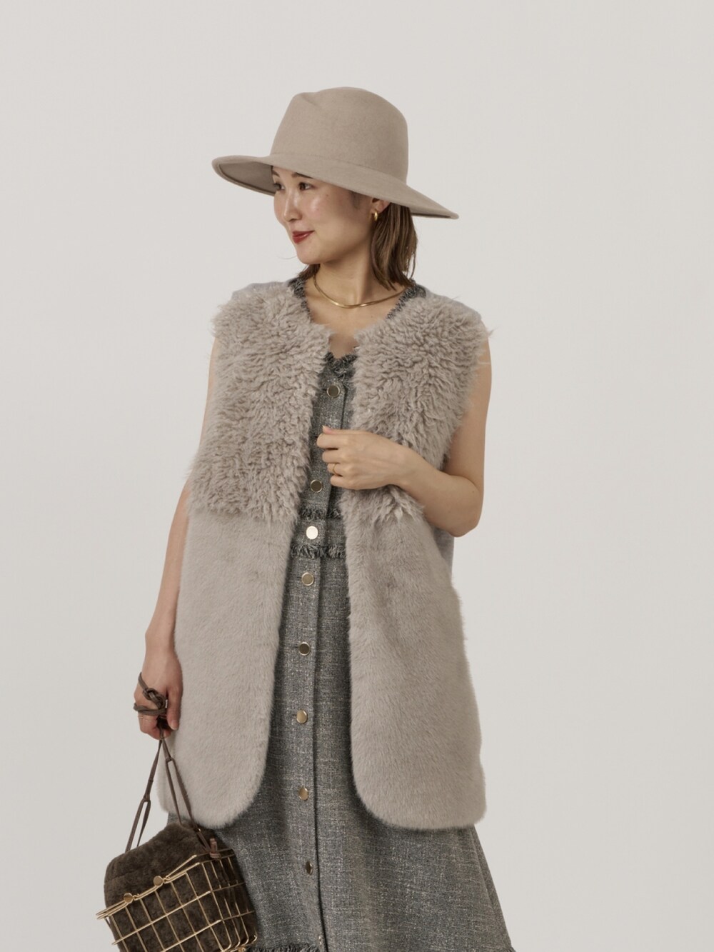 グレー系のベスト、ブラック系のワンピースを着用したレディースの秋コーディネートの2枚目の写真