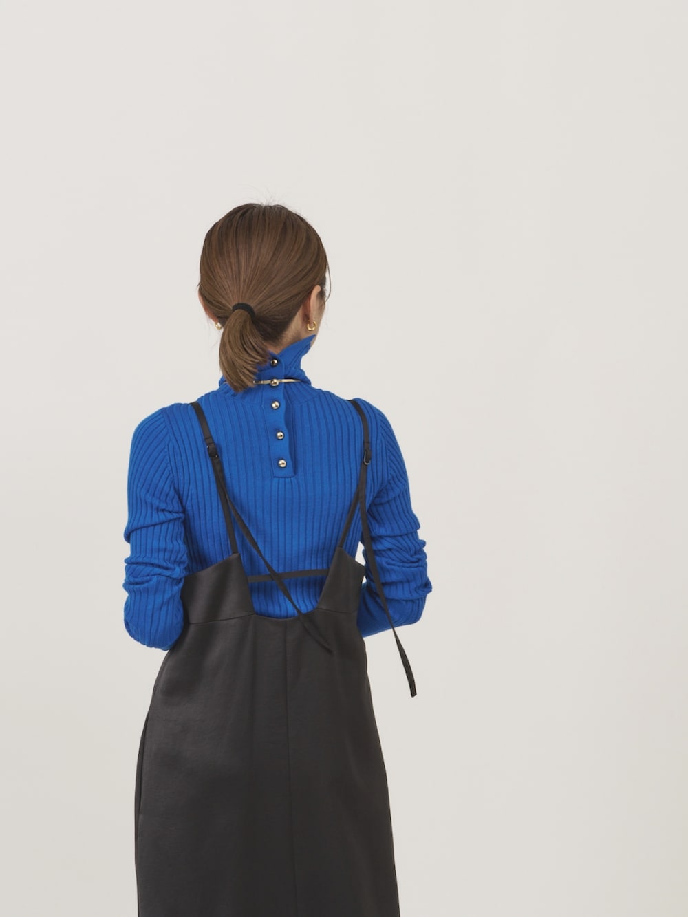 ゴールド系のカーディガン/ボレロ、ブラック系のジャンパースカート、ブルー系のニット/セーターを着用したレディースの秋コーディネートの5枚目の写真