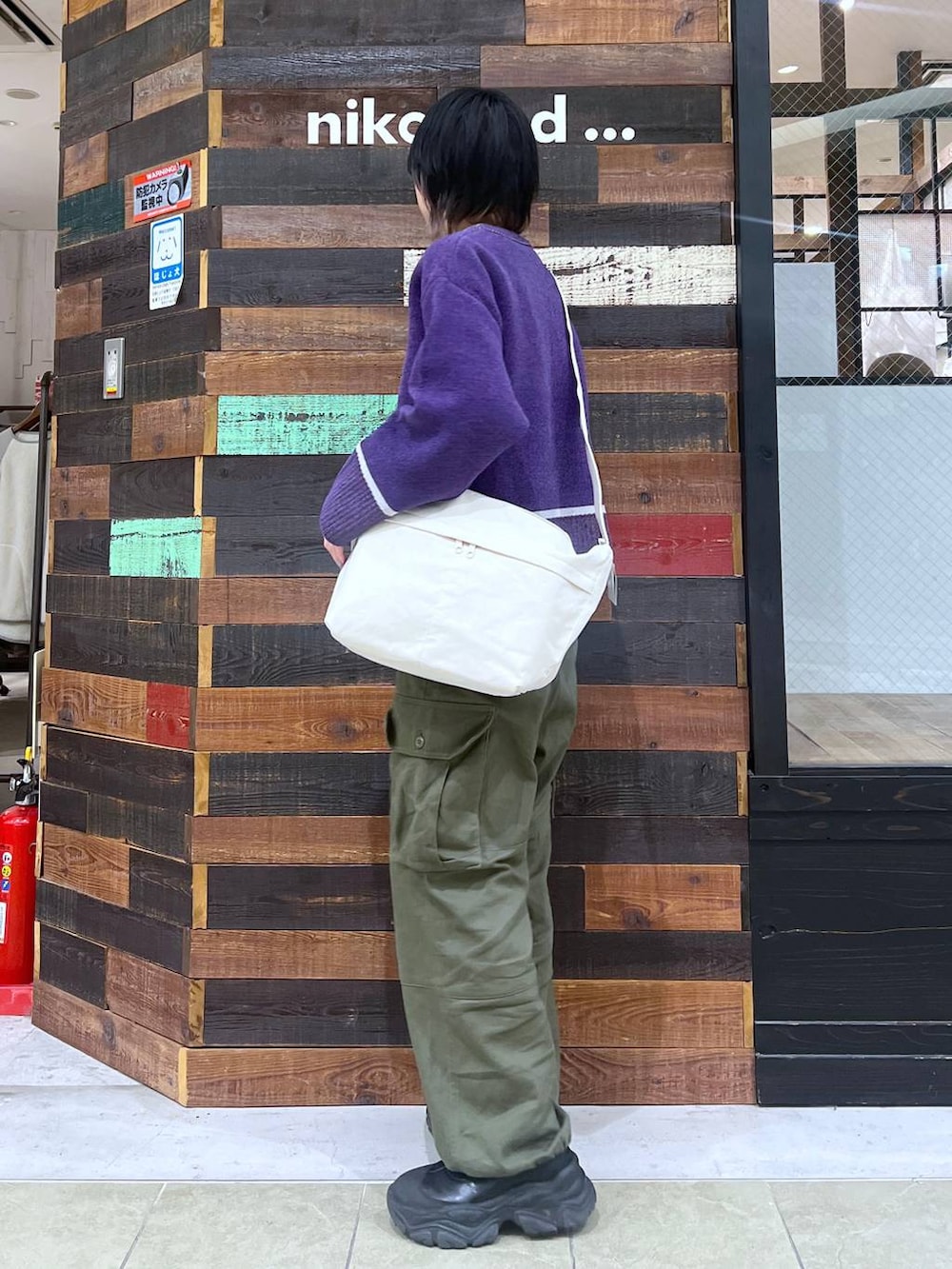 ブラウン系のショルダーバッグ、ブラック系のブーツ、グリーン系のその他パンツを着用したレディースの冬コーディネートの2枚目の写真