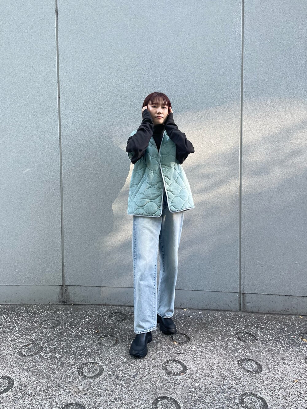 ブルー系のデニムパンツ、ブラック系のブーツ、ブルー系のベストを着用したレディースの秋コーディネートの2枚目の写真