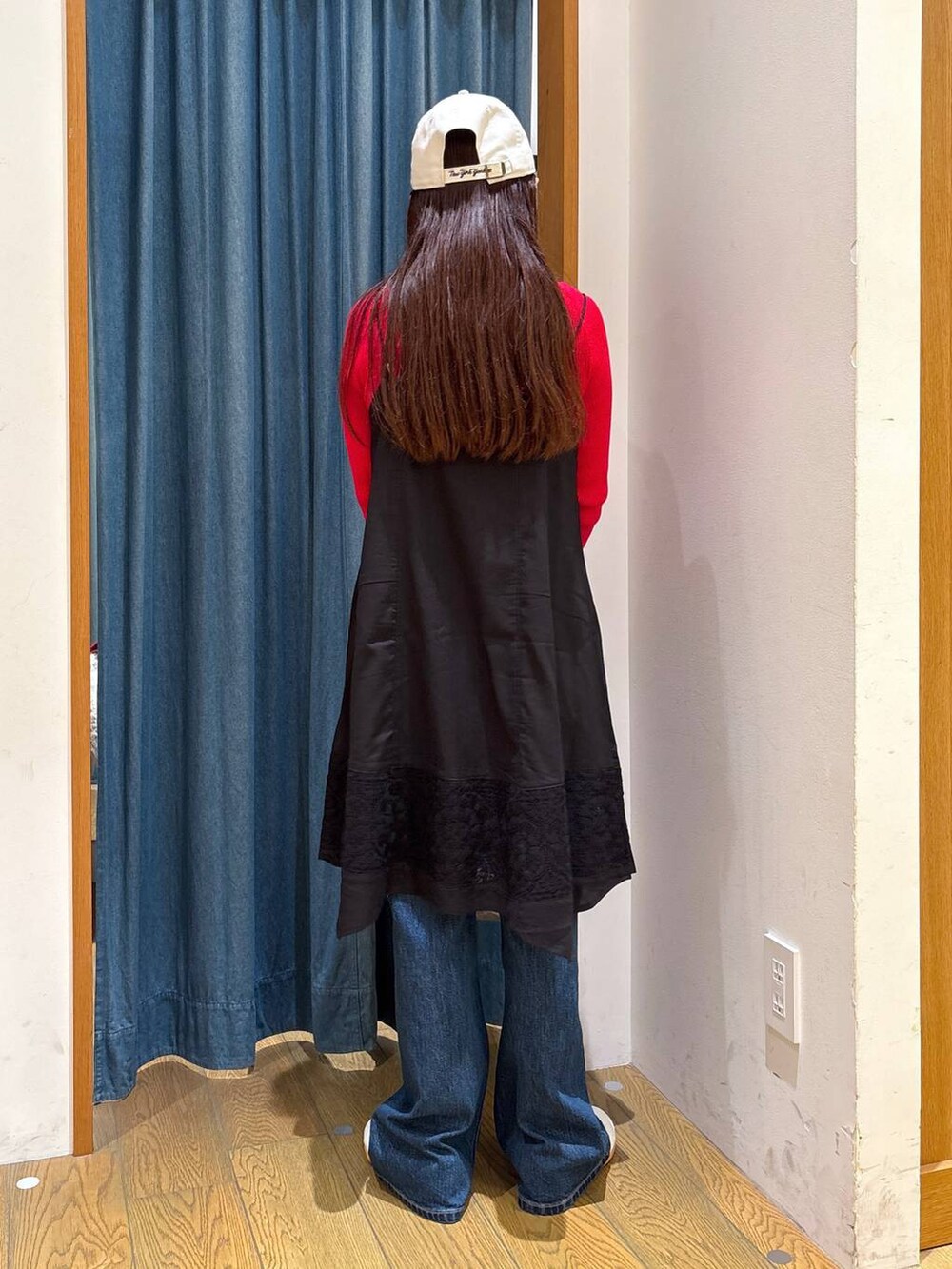 ブルー系のデニムパンツ、ブラック系のワンピース、シルバー系のトートバッグを着用したレディースの秋コーディネートの3枚目の写真