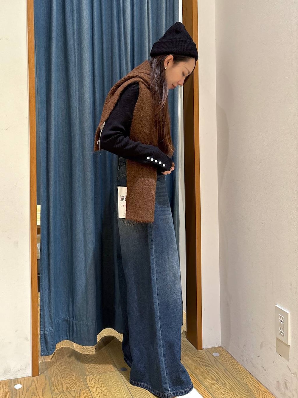 ブラック系のニット/セーター、ブルー系のデニムパンツ、その他のネックレスを着用したレディースの冬コーディネートの2枚目の写真