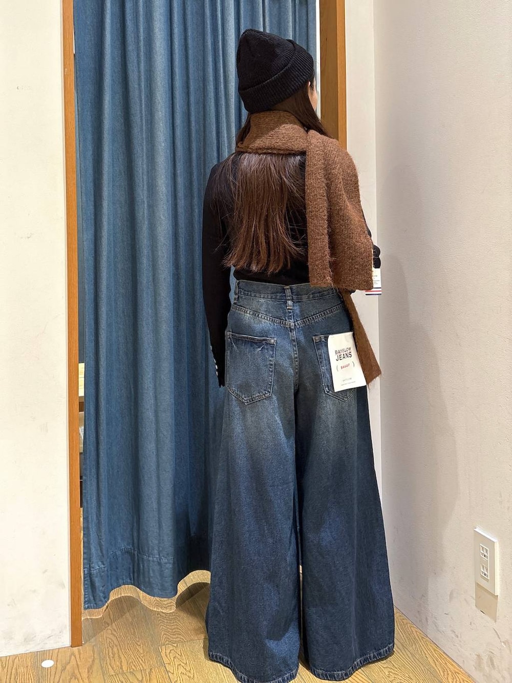 ブラック系のニット/セーター、ブルー系のデニムパンツ、その他のネックレスを着用したレディースの冬コーディネートの3枚目の写真