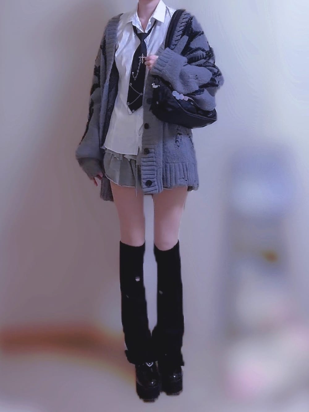 グレー系のカーディガン/ボレロ、グレー系のスカート、ブラック系のショルダーバッグを着用したレディースの秋コーディネートの2枚目の写真