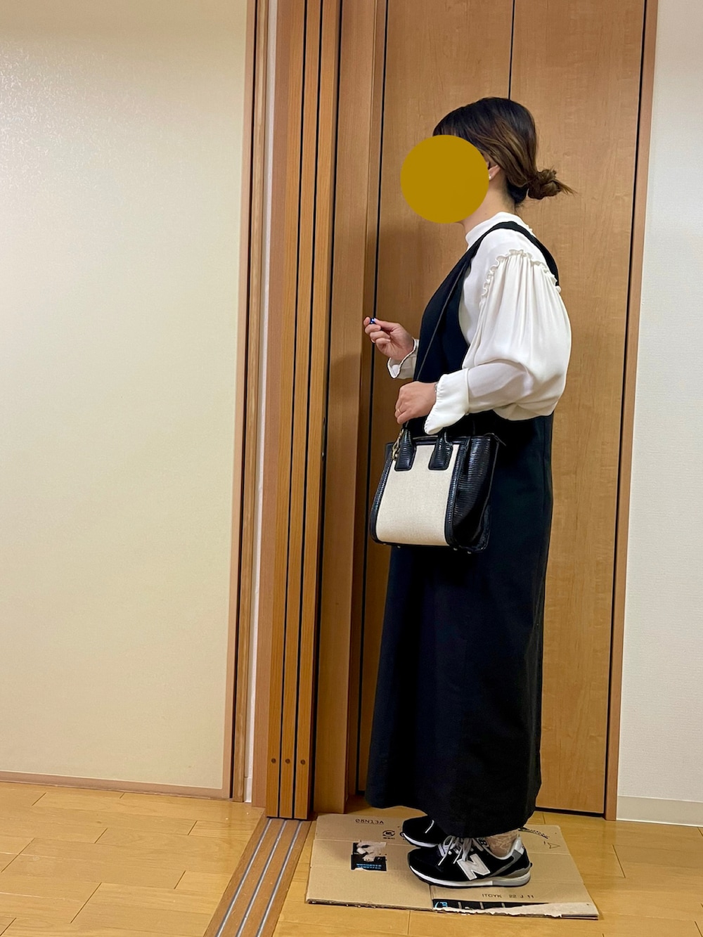 ブラック系のスニーカー、ブラック系のショルダーバッグ、ブラック系のジャンパースカートを着用したレディースの秋コーディネートの2枚目の写真