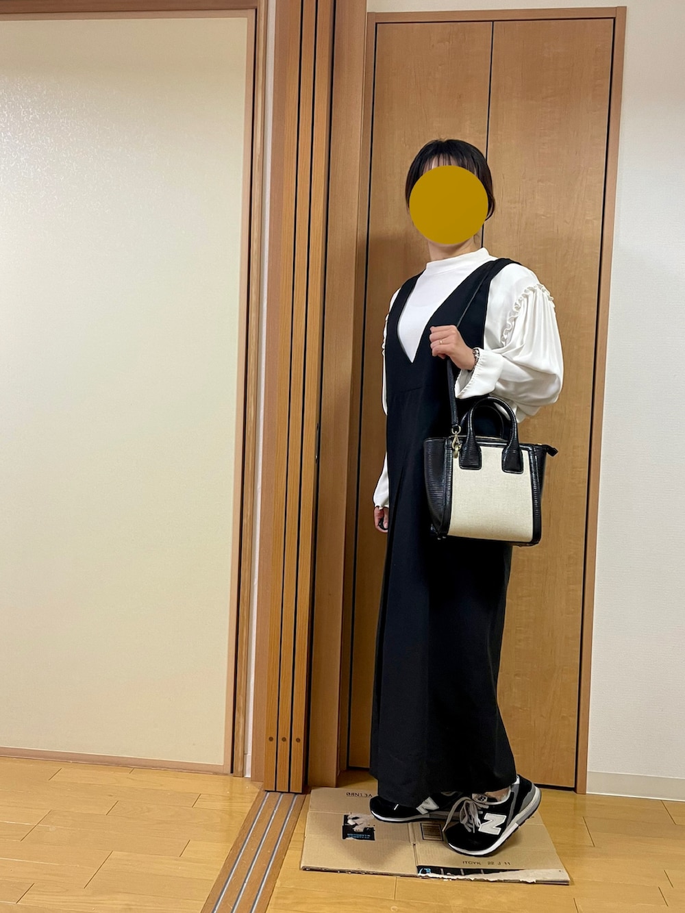 ブラック系のスニーカー、ブラック系のショルダーバッグ、ブラック系のジャンパースカートを着用したレディースの秋コーディネートの4枚目の写真