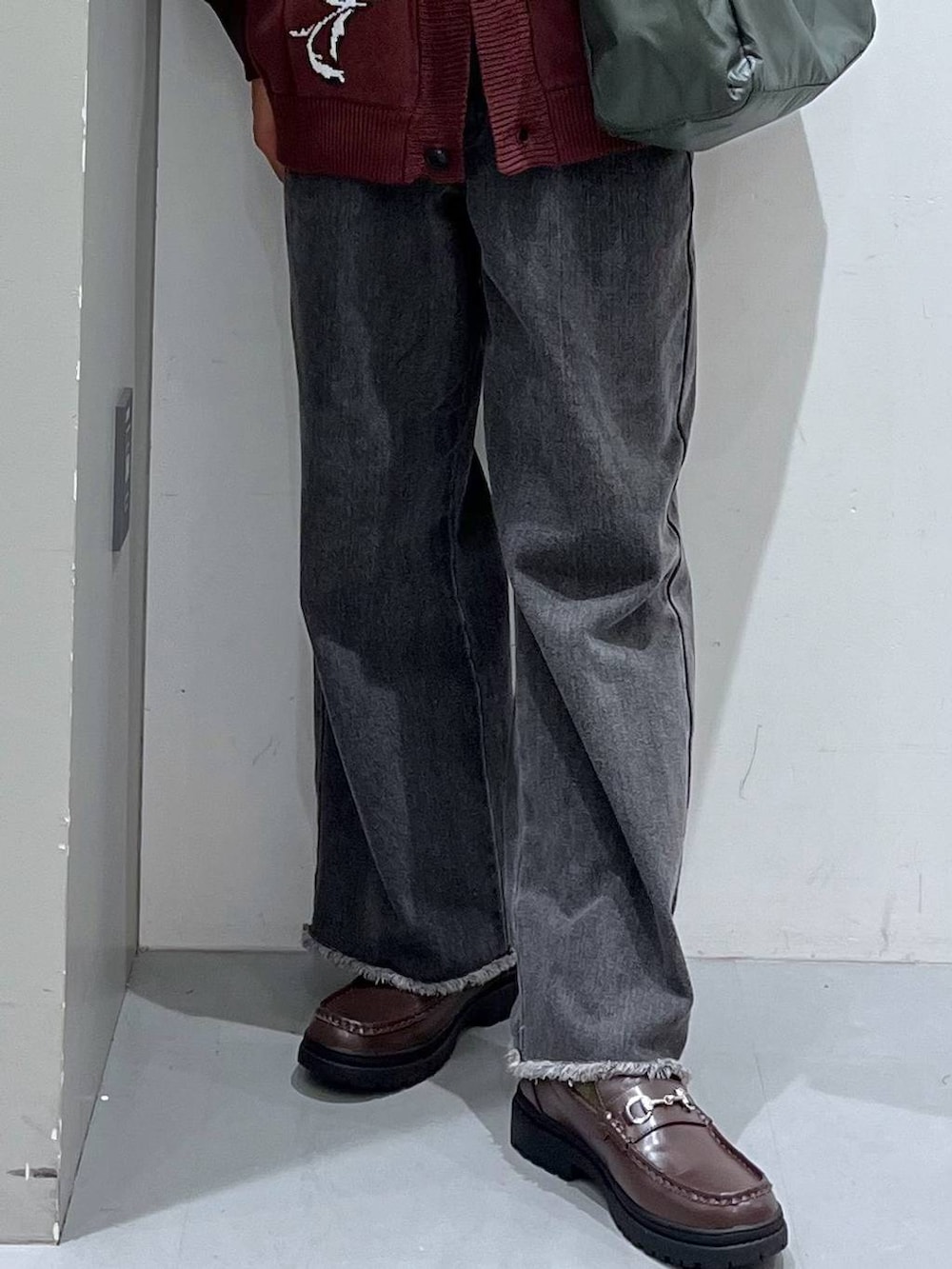 グリーン系のショルダーバッグ、グレー系のデニムパンツ、ブラウン系のローファーを着用したメンズの秋コーディネートの5枚目の写真