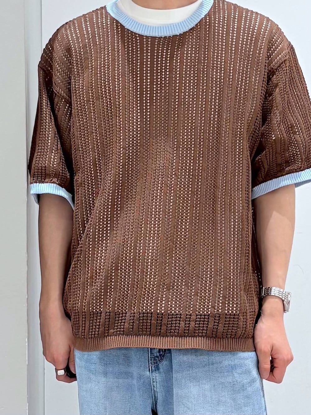 ホワイト系のTシャツ/カットソー、ブルー系のデニムパンツ、ブラウン系のニット/セーターを着用したメンズの春コーディネートの4枚目の写真