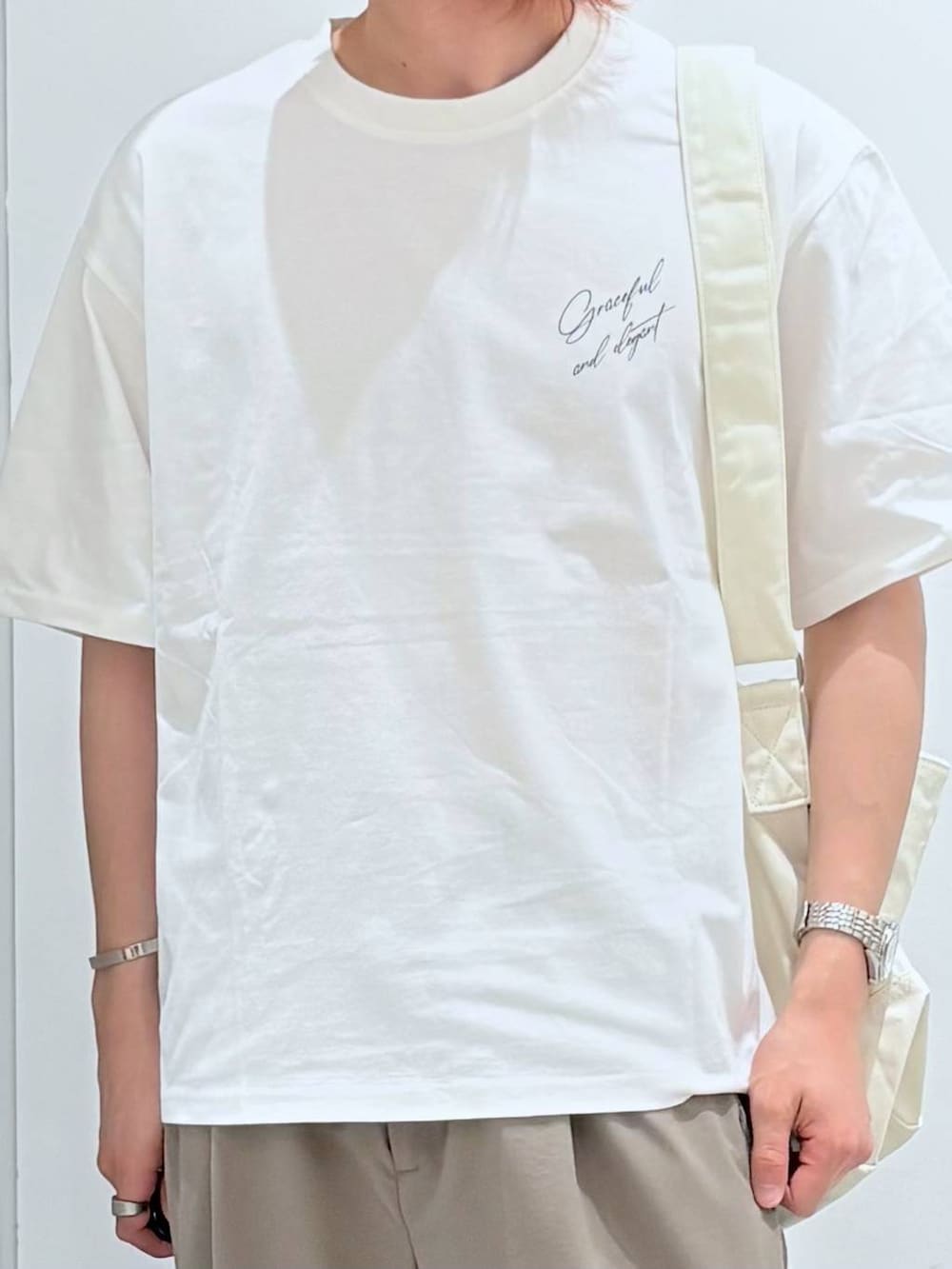 ベージュ系のショルダーバッグ、ベージュ系のその他パンツ、ホワイト系のTシャツ/カットソーを着用したメンズの春コーディネートの4枚目の写真