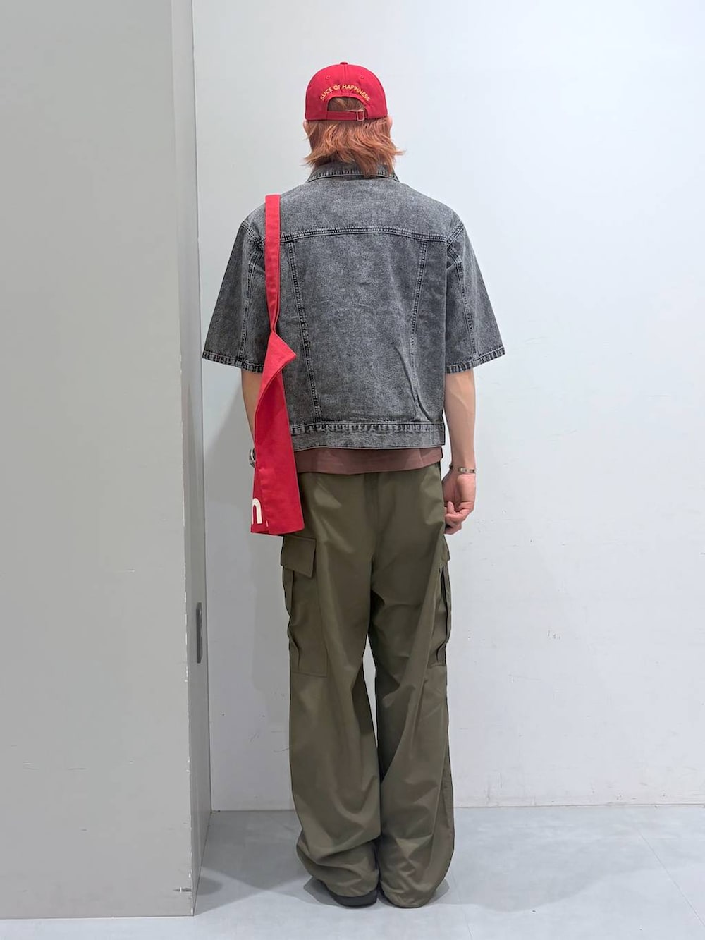 レッド系のトートバッグ、ブラック系のシャツ/ブラウス、ブラウン系のTシャツ/カットソーを着用したメンズの春コーディネートの3枚目の写真