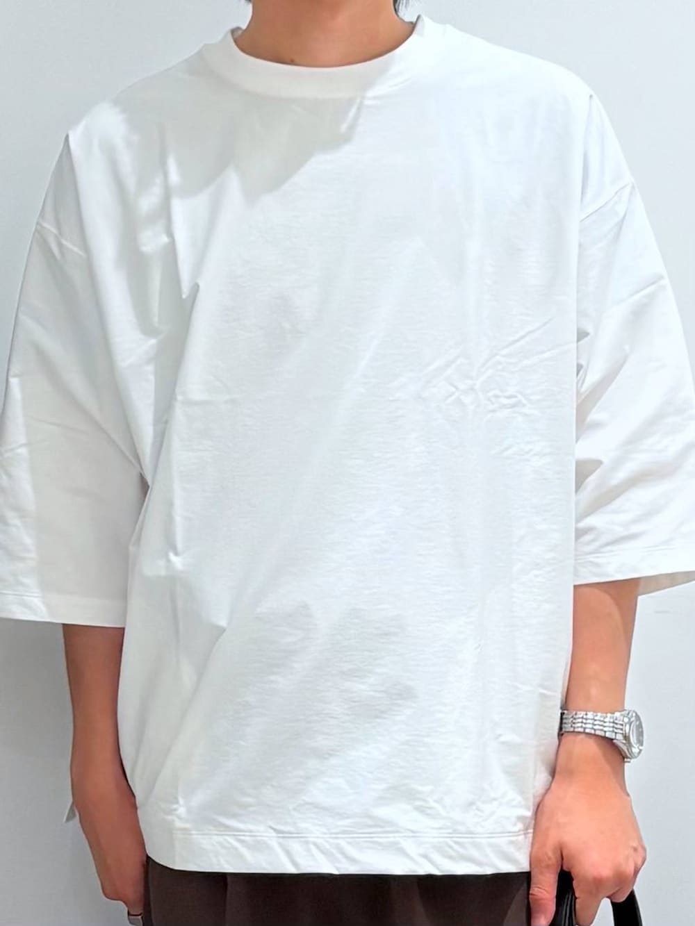 ベージュ系のトートバッグ、ブラウン系のその他パンツ、ホワイト系のTシャツ/カットソーを着用したメンズの夏コーディネートの5枚目の写真