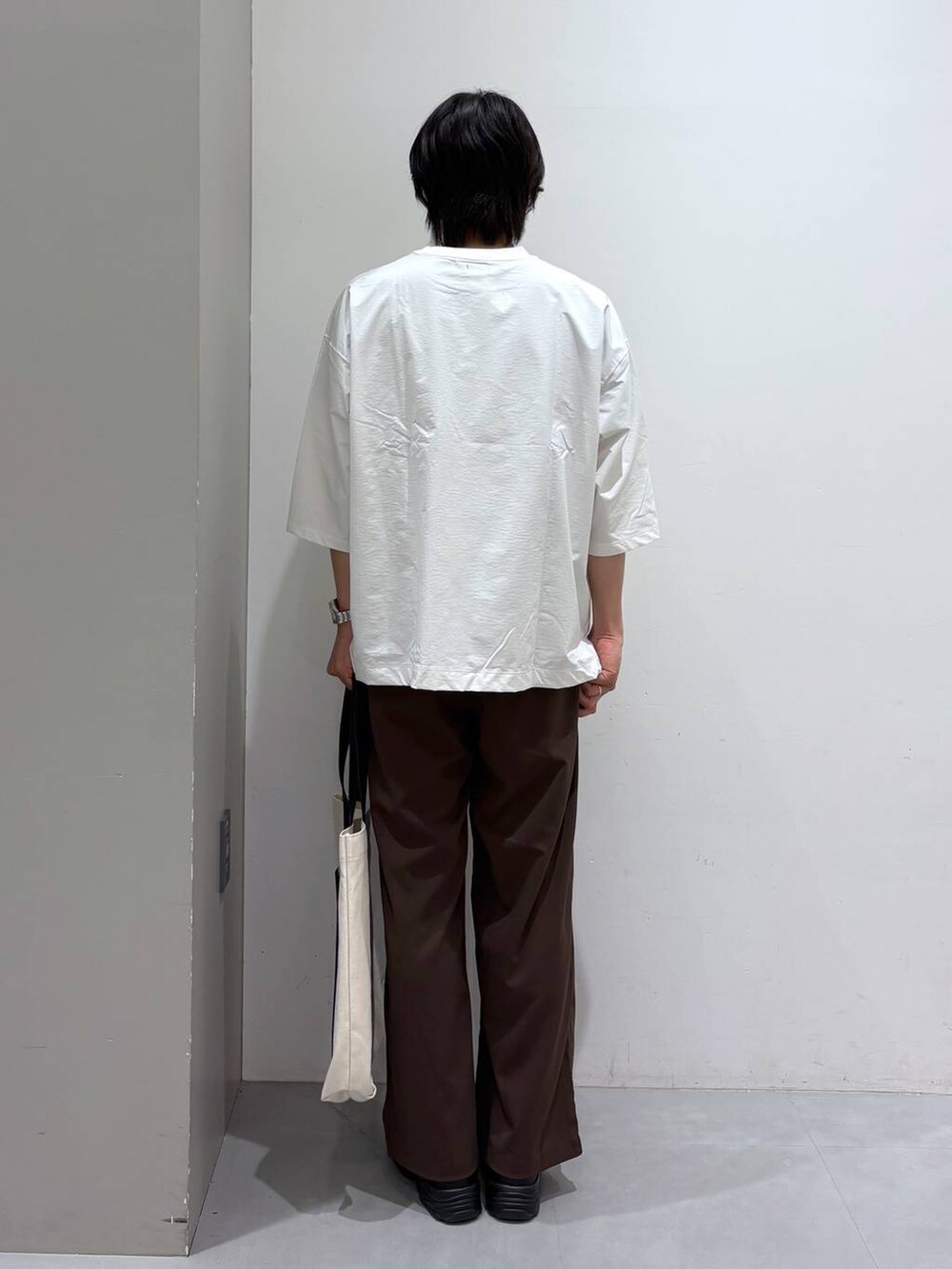 ベージュ系のトートバッグ、ブラウン系のその他パンツ、ホワイト系のTシャツ/カットソーを着用したメンズの夏コーディネートの3枚目の写真