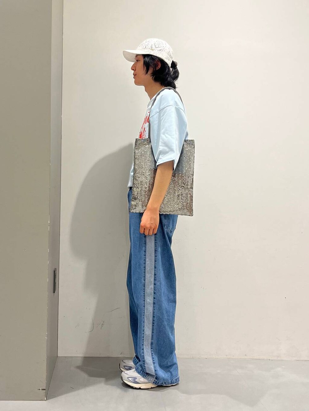 グレー系のトートバッグ、ブルー系のデニムパンツ、ブルー系のTシャツ/カットソーを着用したメンズの夏コーディネートの3枚目の写真