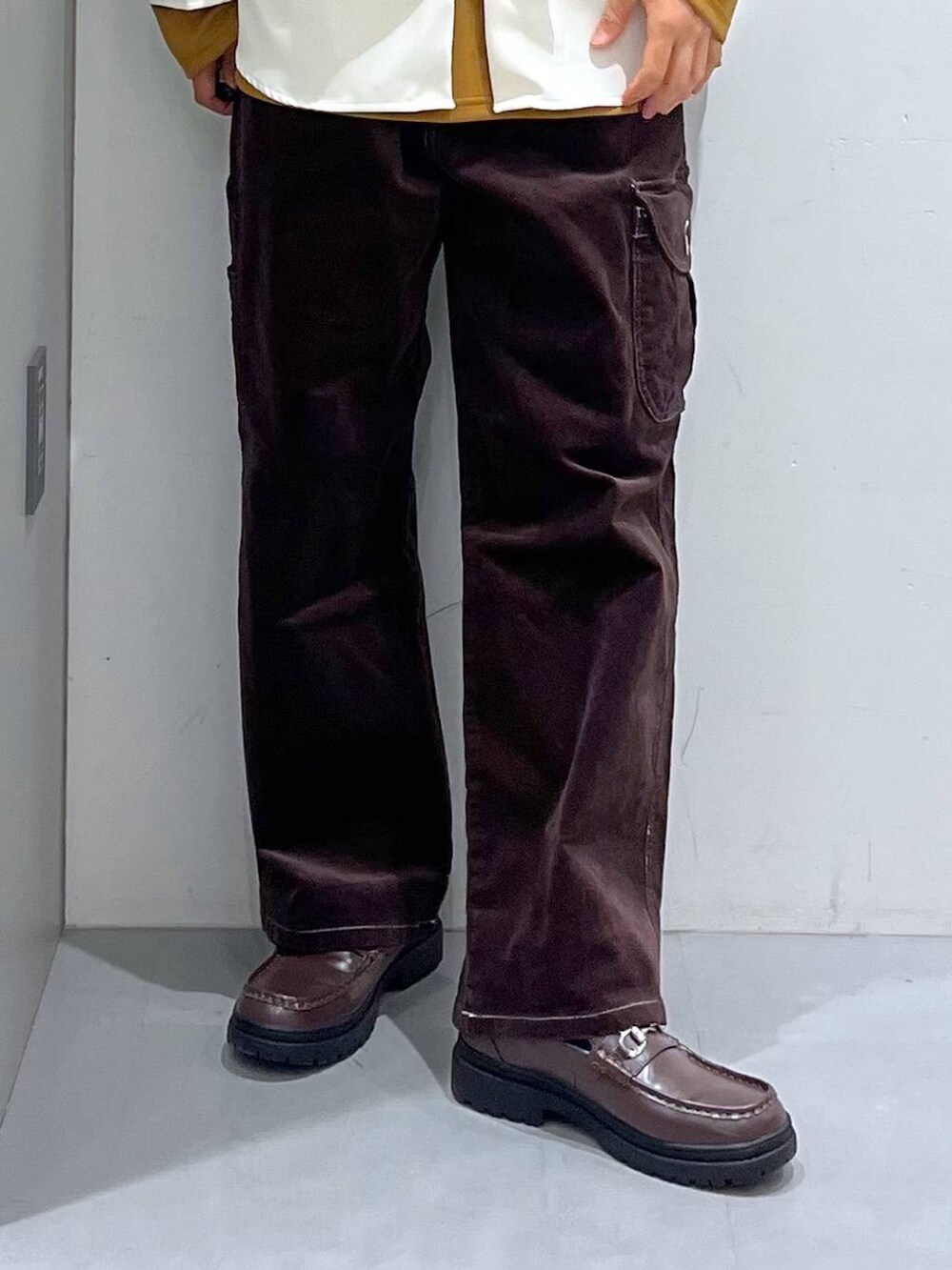 イエロー系のTシャツ/カットソー、ブラウン系のその他パンツ、ベージュ系のショルダーバッグを着用したメンズの冬コーディネートの5枚目の写真