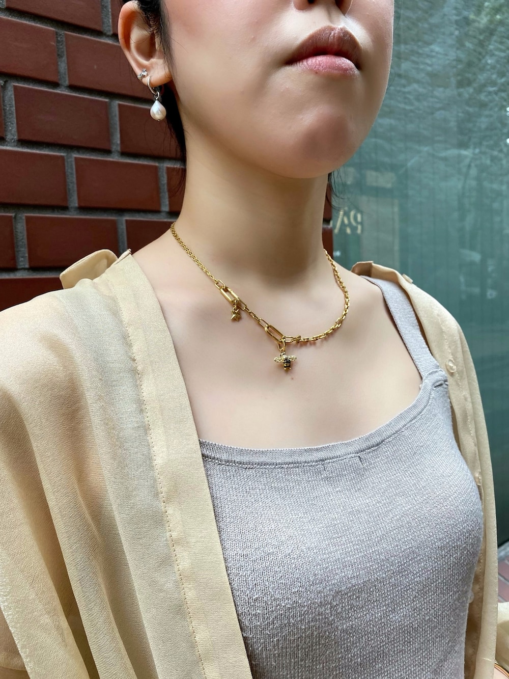 ゴールド系のチャーム、ゴールド系のチャーム、シルバー系のピアス（両耳用）を着用したレディースの夏コーディネートの2枚目の写真