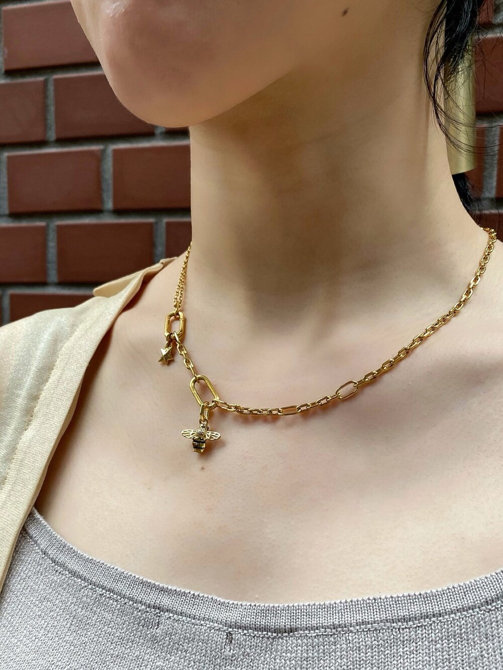 ゴールド系のチャーム、ゴールド系のチャーム、シルバー系のピアス（両耳用）を着用したレディースの夏コーディネートの3枚目の写真