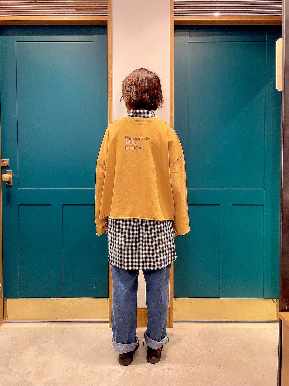 イエロー系のスウェット、ブラック系のシャツ/ブラウス、ブルー系のデニムパンツを着用したレディースの秋コーディネートの2枚目の写真