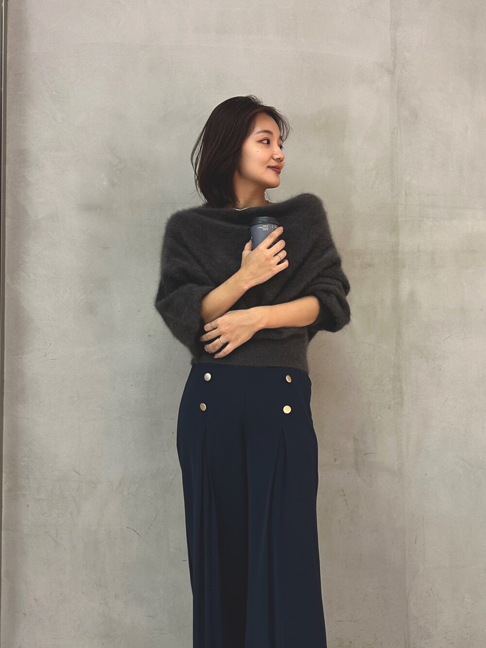 グレー系のニット/セーター、ブルー系のスラックスを着用したレディースの秋コーディネートの2枚目の写真