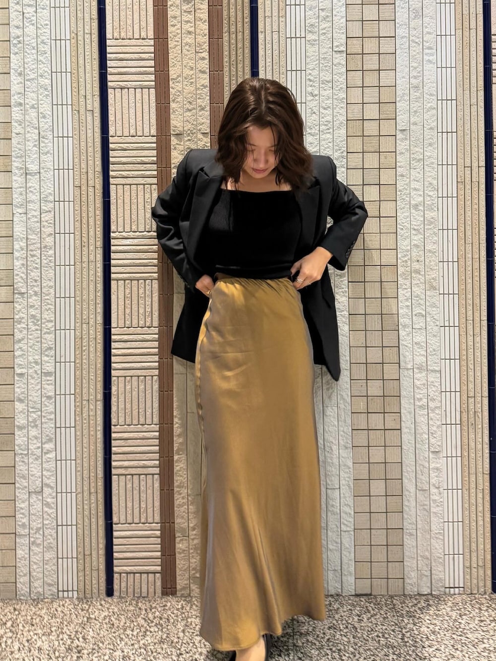 ブラウン系のスカート、ブラック系のパンプス、ブラック系のテーラードジャケットを着用したレディースの秋コーディネートの3枚目の写真