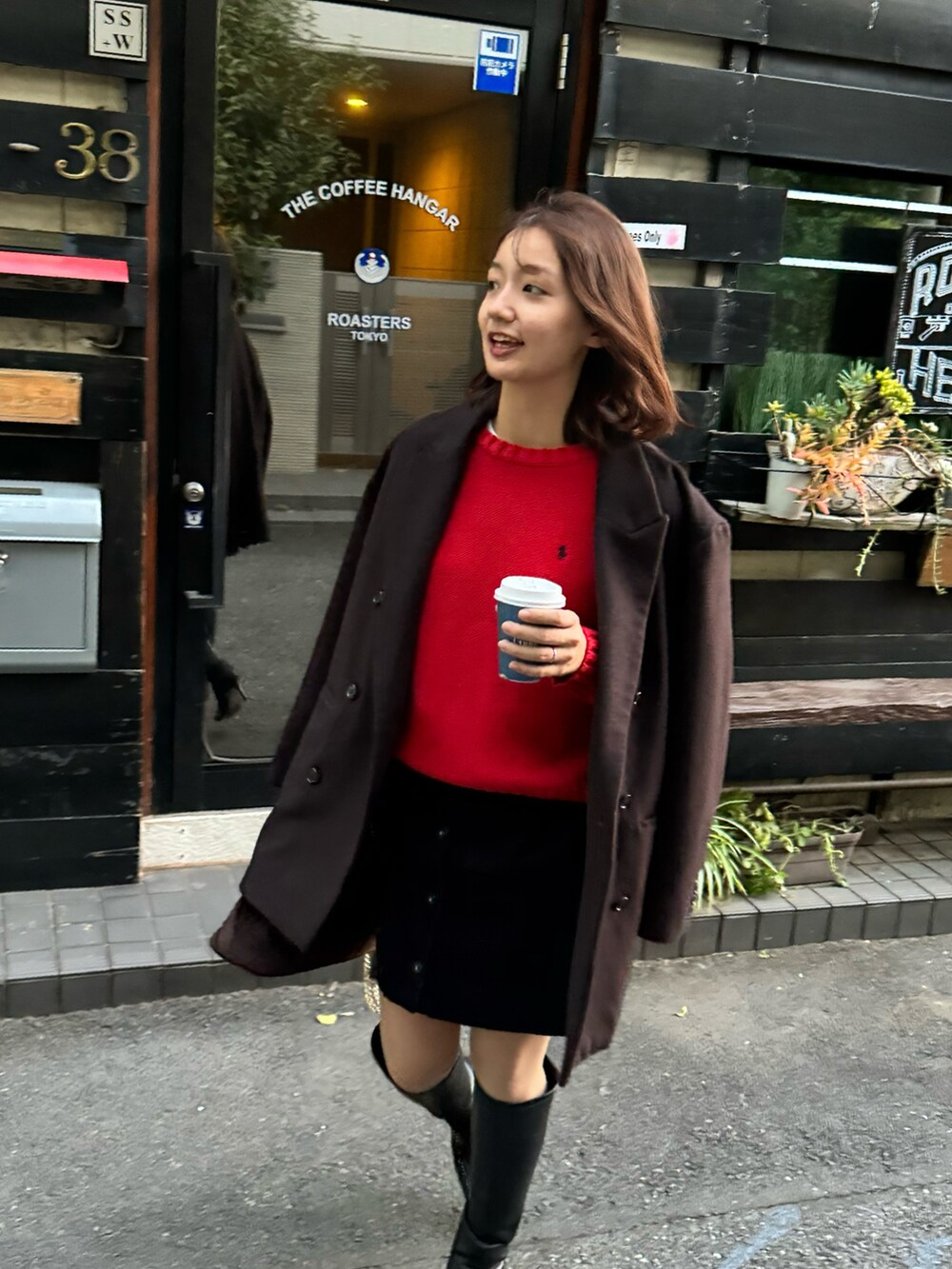 レッド系のトップス、ブラウン系のジャケット/アウター、ブラック系のブーツを着用したレディースの冬コーディネートの2枚目の写真