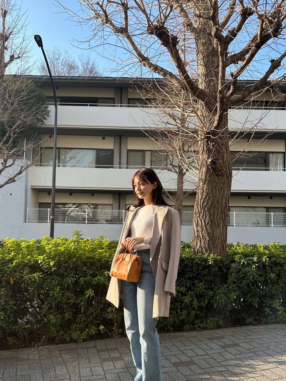 ベージュ系のテーラードジャケット、ブルー系のデニムパンツを着用したレディースの春コーディネートの3枚目の写真