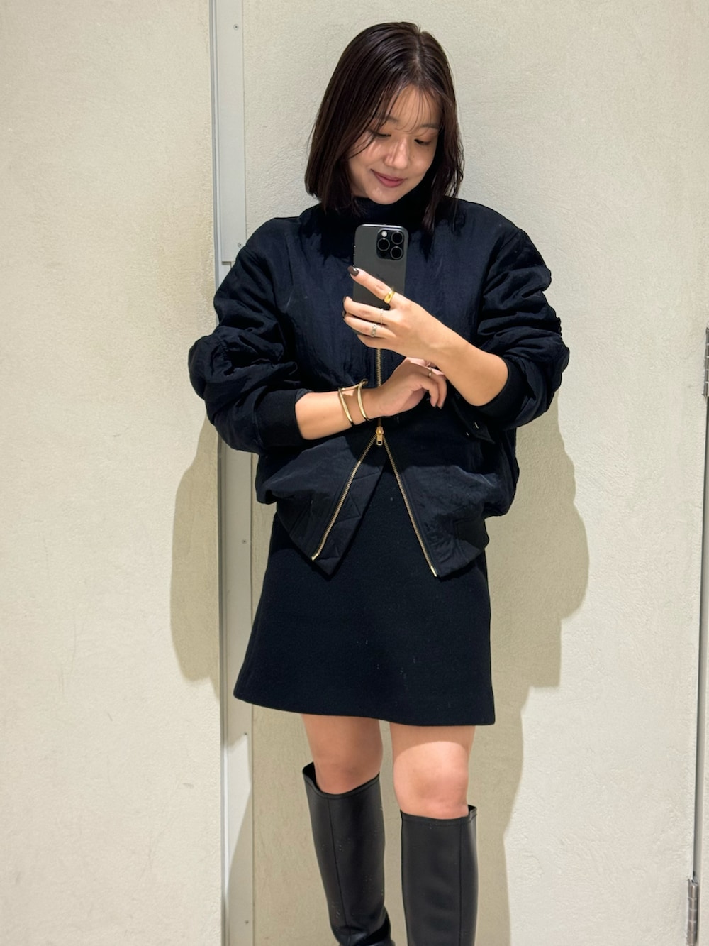 グレー系のニット/セーター、ブラック系のスカート、ブラック系のブルゾンを着用したレディースの秋コーディネートの2枚目の写真