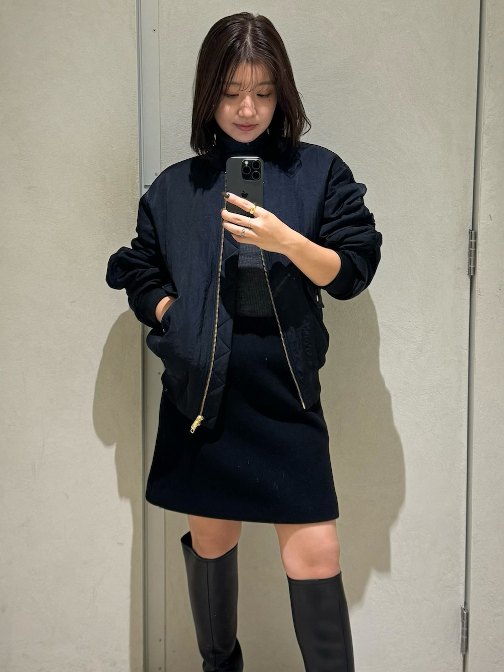 グレー系のニット/セーター、ブラック系のスカート、ブラック系のブルゾンを着用したレディースの秋コーディネートの3枚目の写真