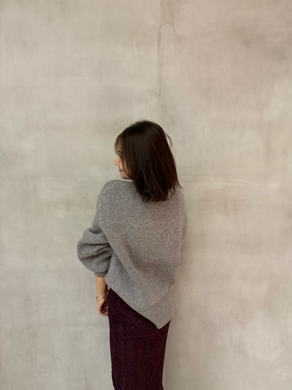 グレー系のニット/セーター、レッド系のスカート、ブラウン系のパンプスを着用したレディースの秋コーディネートの3枚目の写真