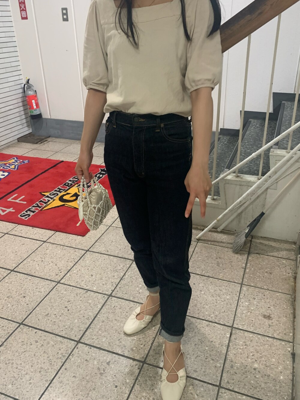 ブラック系のデニムパンツ、ホワイト系のサンダル、ベージュ系のTシャツ/カットソーを着用したレディースの夏コーディネートの3枚目の写真