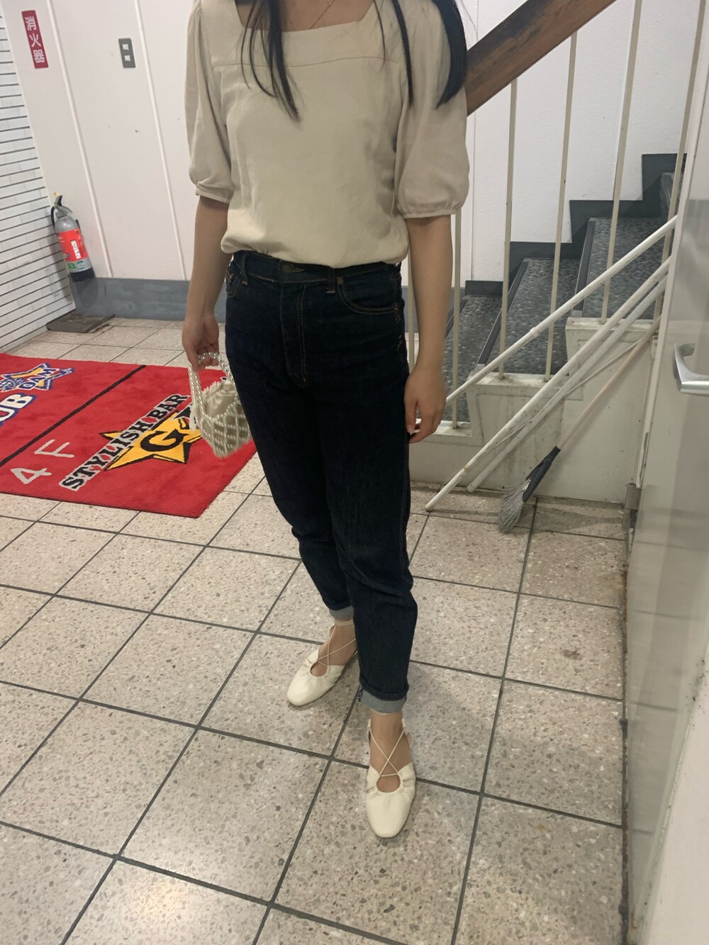 ブラック系のデニムパンツ、ホワイト系のサンダル、ベージュ系のTシャツ/カットソーを着用したレディースの夏コーディネートの2枚目の写真