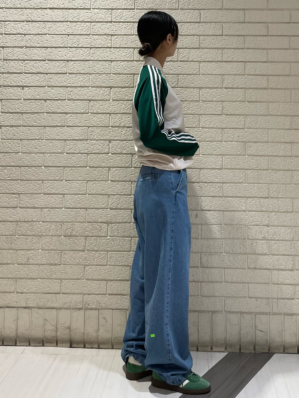 ホワイト系のトップス、ブルー系のデニムパンツ、グリーン系のスニーカーを着用したレディースの春コーディネートの3枚目の写真