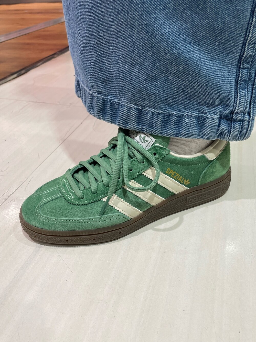 ホワイト系のトップス、ブルー系のデニムパンツ、グリーン系のスニーカーを着用したレディースの春コーディネートの4枚目の写真