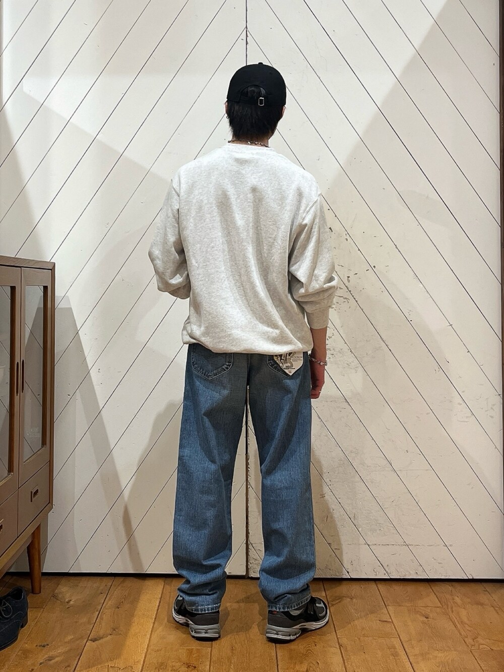 グレー系のスウェット、ブルー系のデニムパンツ、ブラック系のスニーカーを着用したメンズの秋コーディネートの3枚目の写真