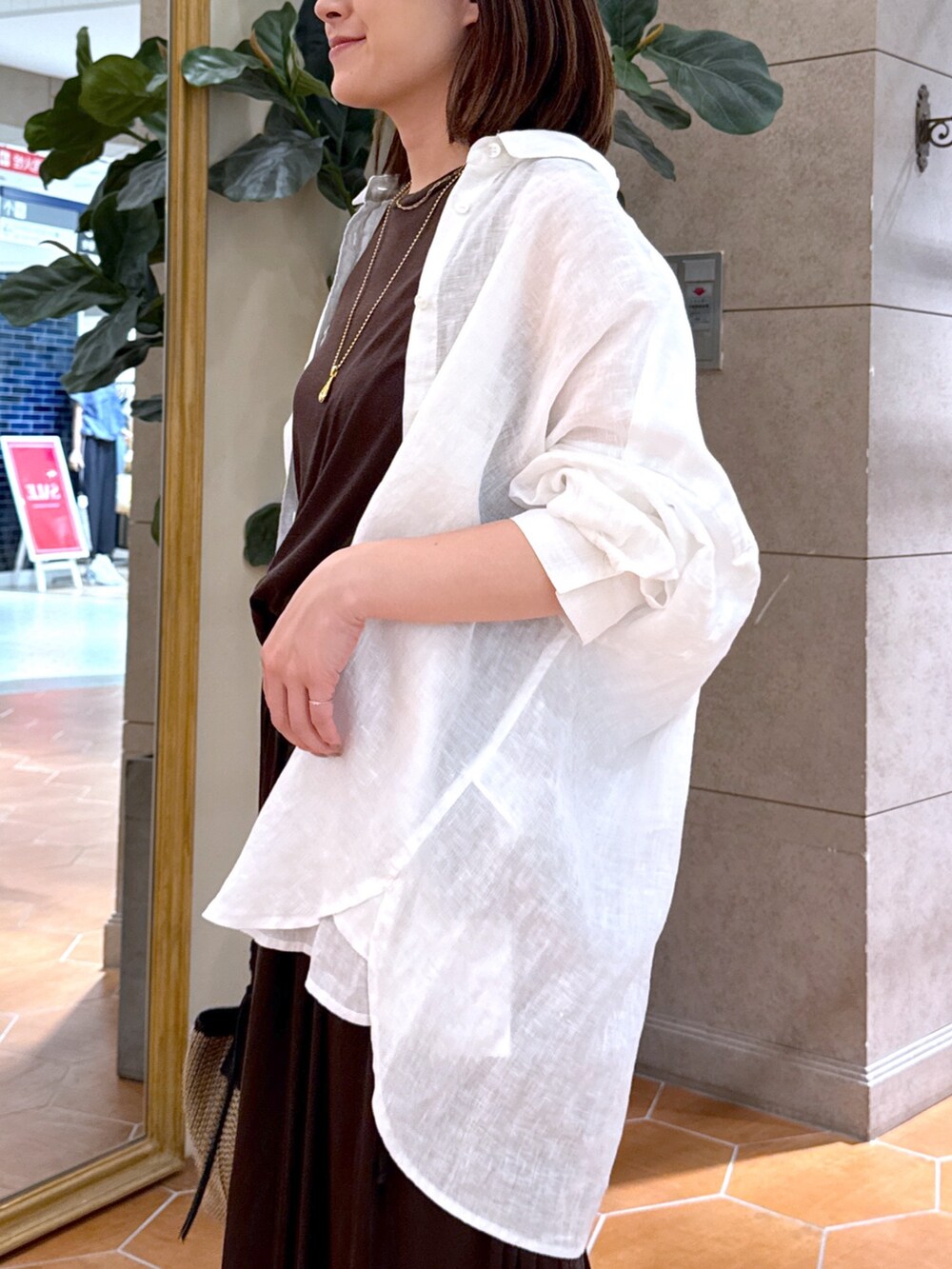 ブラウン系のワンピース、ブラック系のハンドバッグ、ブラック系のサンダルを着用したレディースの夏コーディネートの5枚目の写真