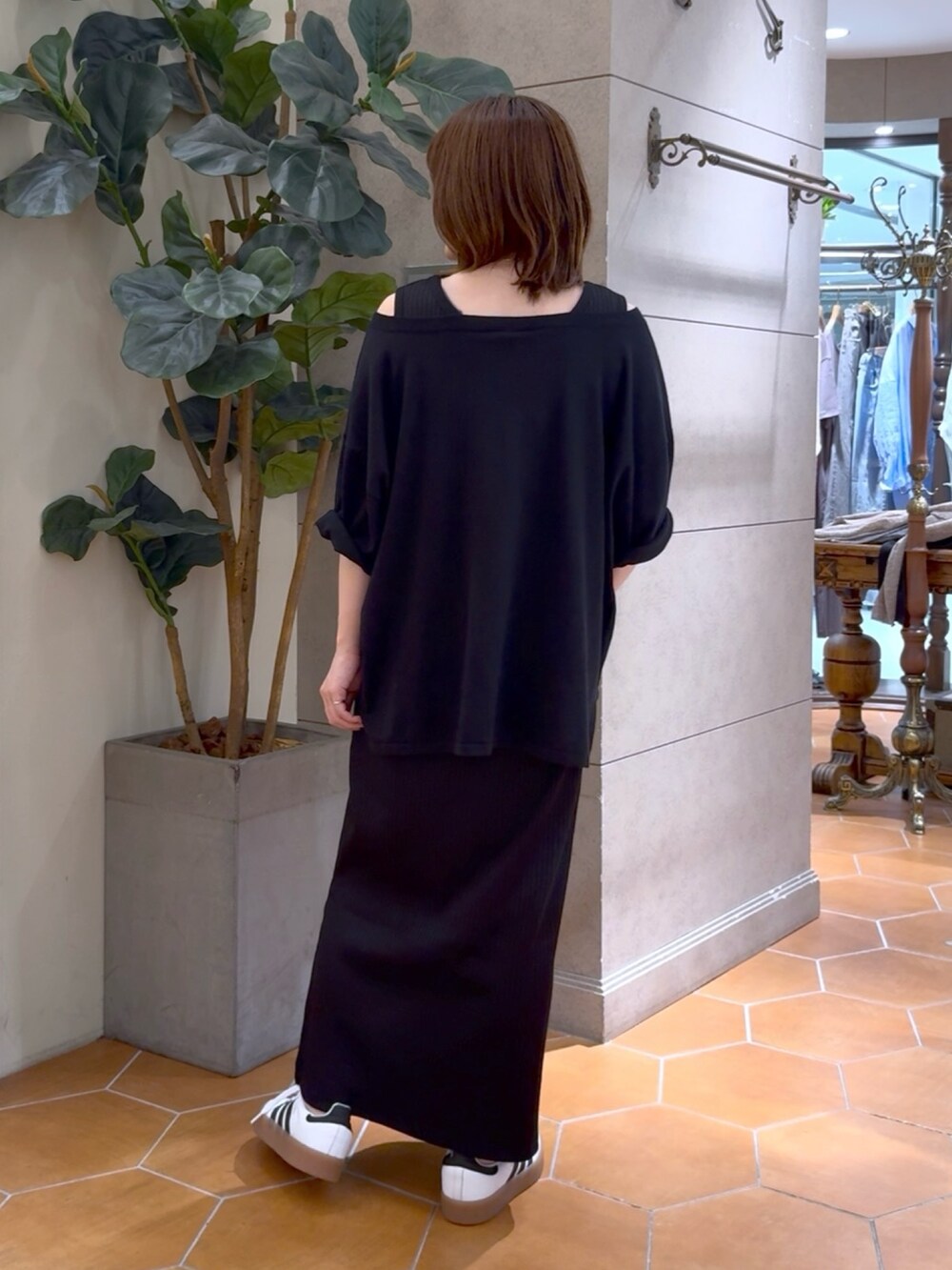 ブラック系のニット/セーター、ブラック系のワンピース、ゴールド系のネックレスを着用したレディースの夏コーディネートの2枚目の写真