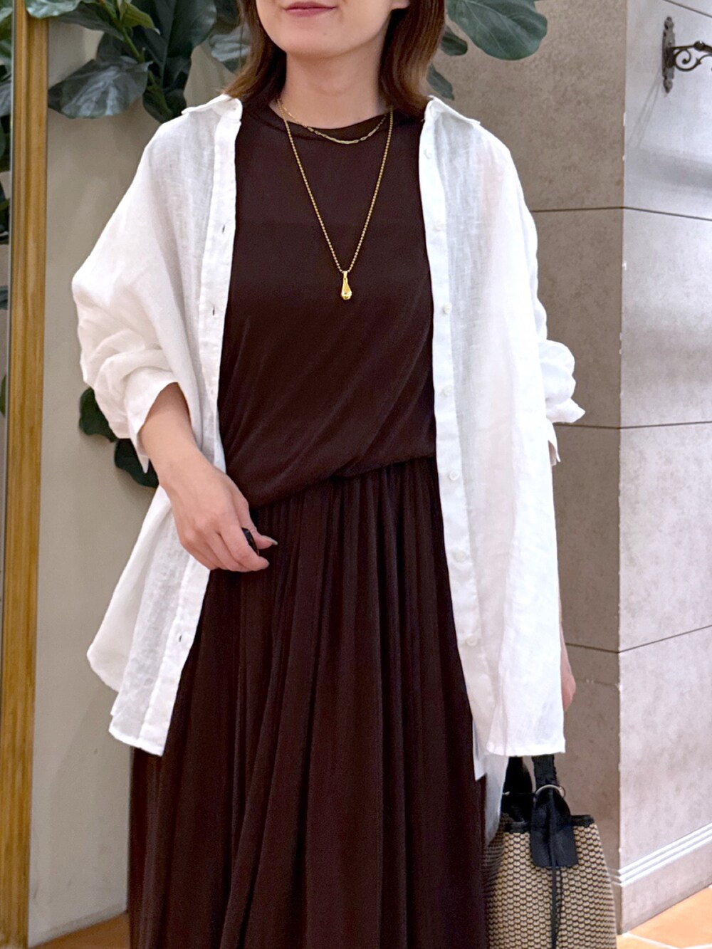 ブラウン系のワンピース、ブラック系のハンドバッグ、ブラック系のサンダルを着用したレディースの夏コーディネートの4枚目の写真