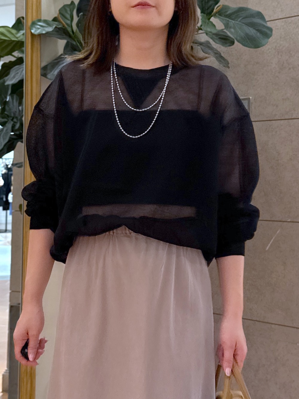 ブラック系のニット/セーター、グレー系のスカート、イエロー系のボストンバッグを着用したレディースの夏コーディネートの2枚目の写真