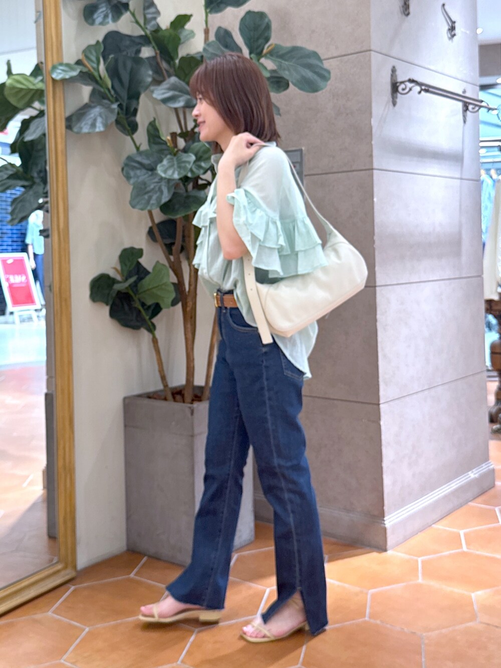 ブルー系のデニムパンツ、ベージュ系のサンダル、グリーン系のシャツ/ブラウスを着用したレディースの夏コーディネートの2枚目の写真