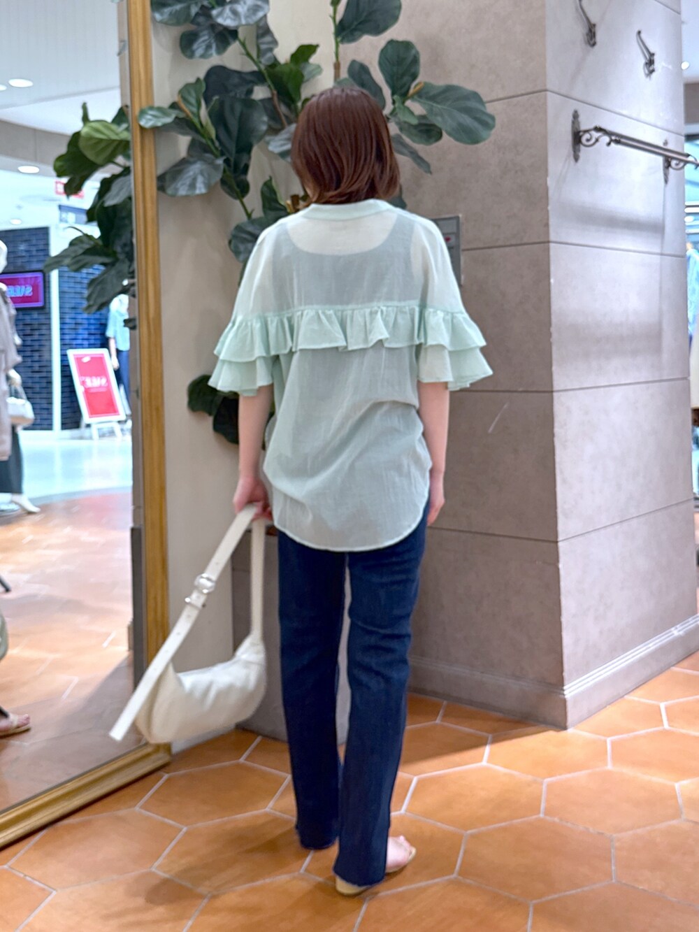 ブルー系のデニムパンツ、ベージュ系のサンダル、グリーン系のシャツ/ブラウスを着用したレディースの夏コーディネートの3枚目の写真