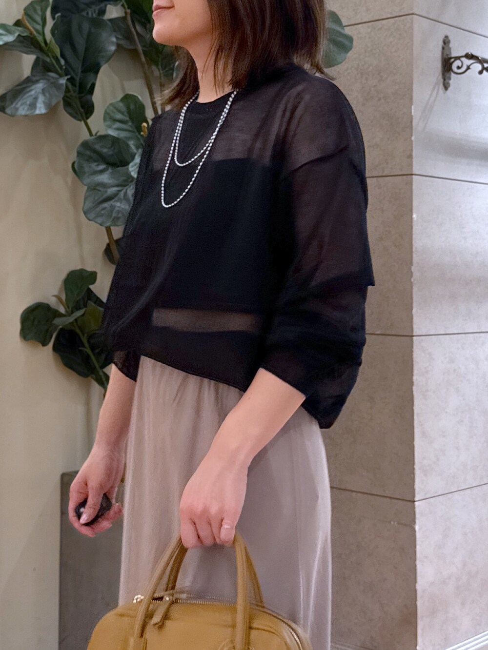 ブラック系のニット/セーター、グレー系のスカート、イエロー系のボストンバッグを着用したレディースの夏コーディネートの3枚目の写真