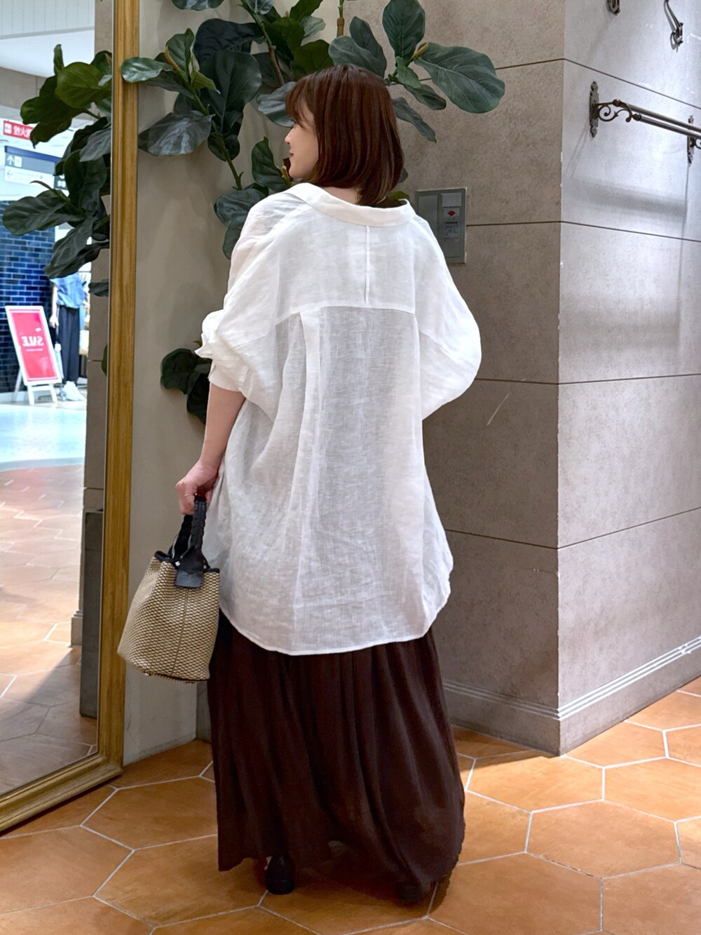 ブラウン系のワンピース、ブラック系のハンドバッグ、ブラック系のサンダルを着用したレディースの夏コーディネートの3枚目の写真