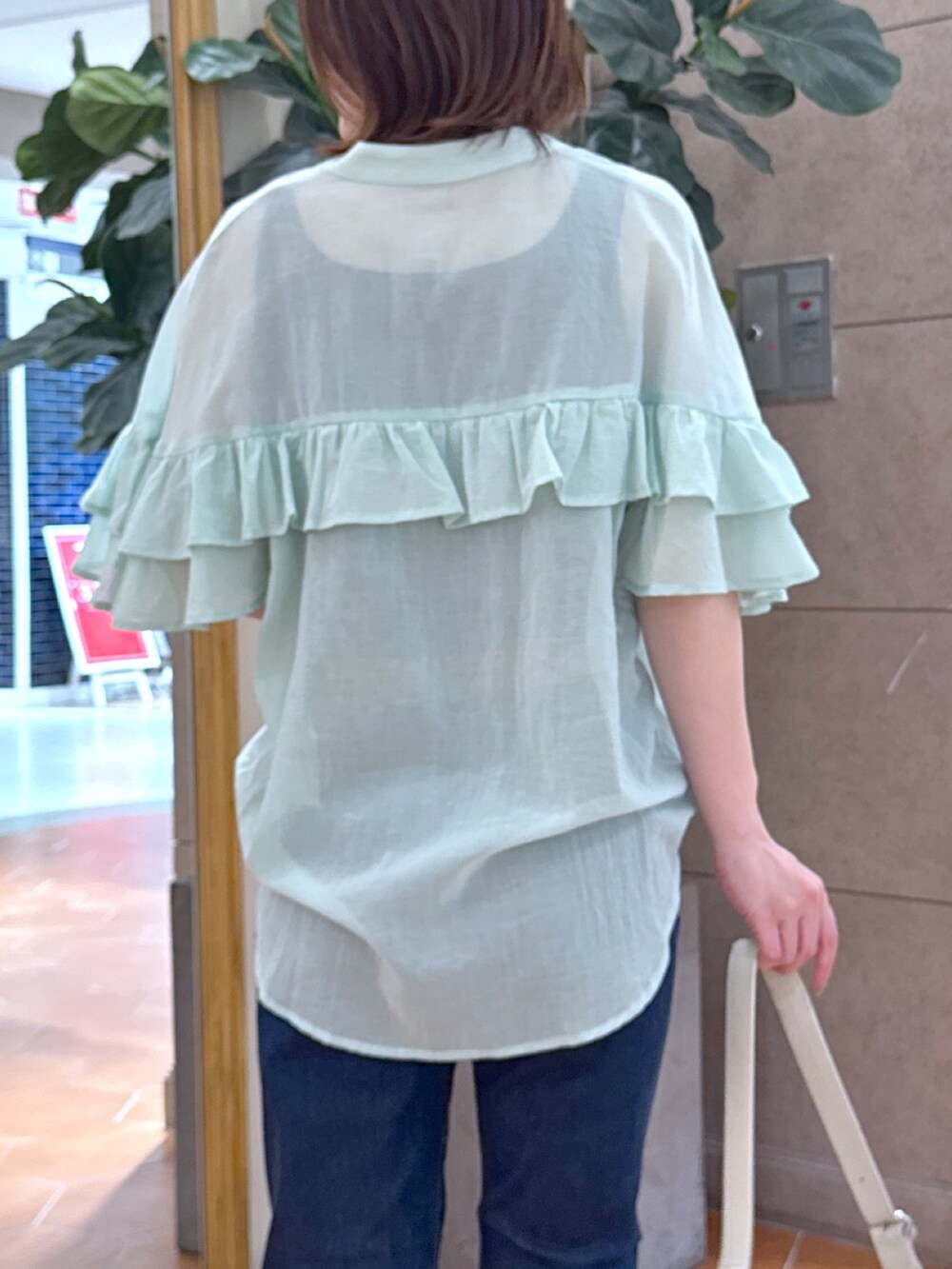 ブルー系のデニムパンツ、ベージュ系のサンダル、グリーン系のシャツ/ブラウスを着用したレディースの夏コーディネートの6枚目の写真