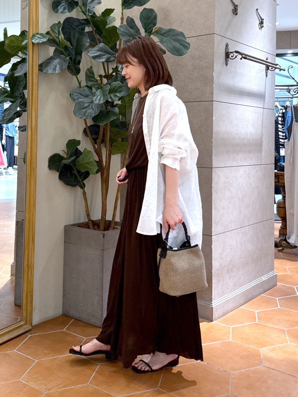 ブラウン系のワンピース、ブラック系のハンドバッグ、ブラック系のサンダルを着用したレディースの夏コーディネートの2枚目の写真