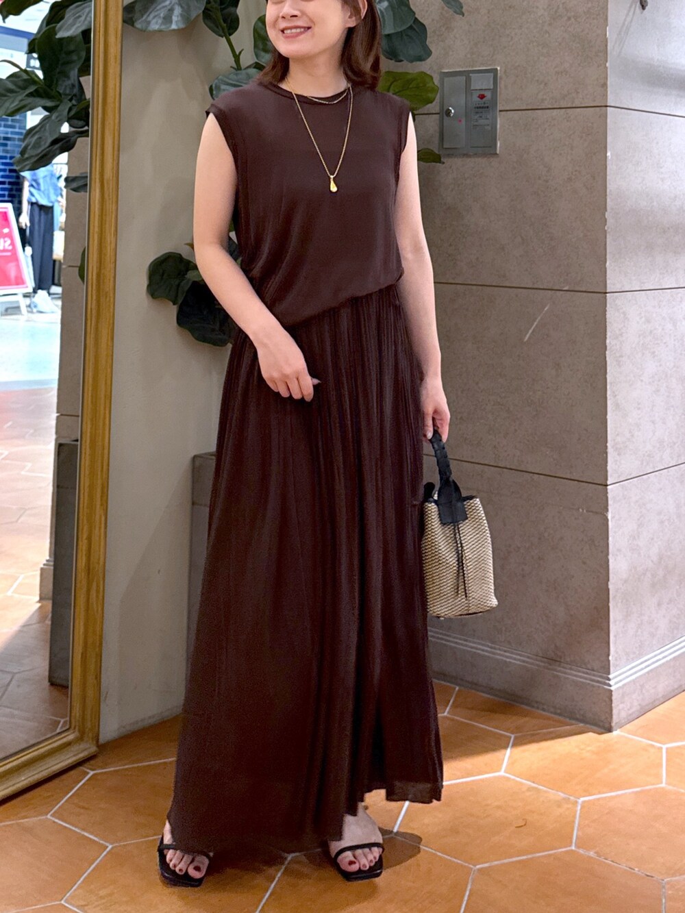 ブラウン系のワンピース、ブラック系のハンドバッグ、ブラック系のサンダルを着用したレディースの夏コーディネートの6枚目の写真