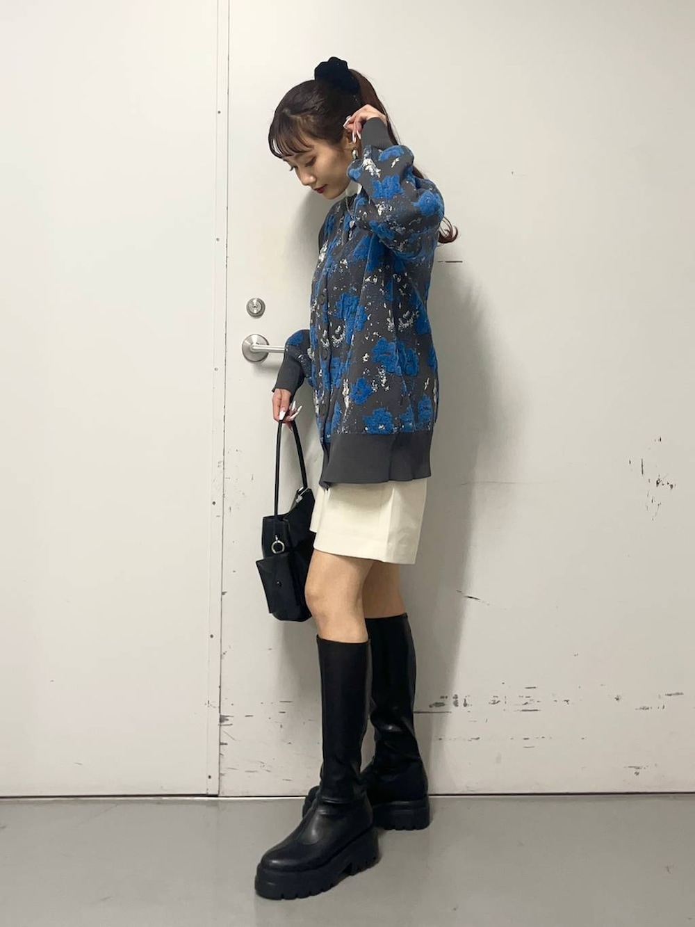 ホワイト系のニット/セーター、ブラック系のブーツ、ブルー系のカーディガン/ボレロを着用したレディースの冬コーディネートの2枚目の写真