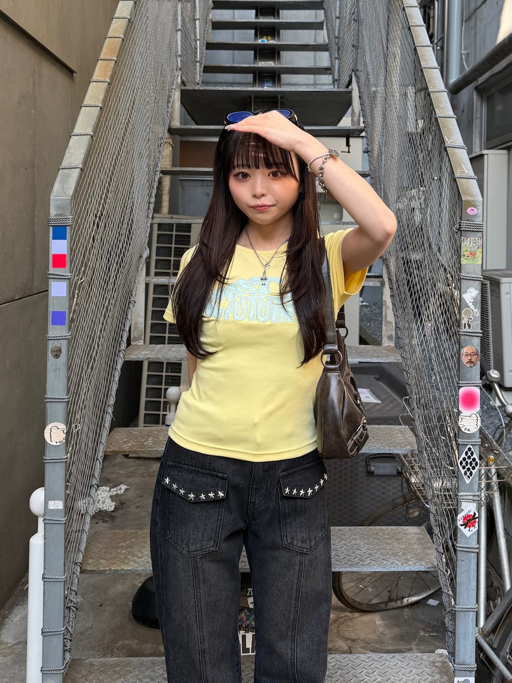イエロー系のTシャツ/カットソー、ブラック系のデニムパンツ、ブラック系のサンダルを着用したレディースの春コーディネートの5枚目の写真
