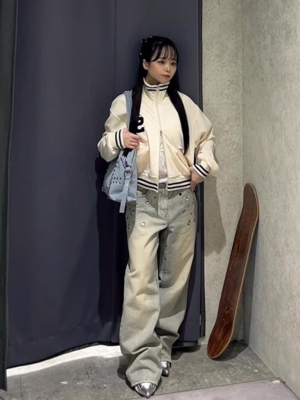 ホワイト系のブルゾン、ホワイト系のキャミソール、ブルー系のショルダーバッグを着用したレディースの冬コーディネートの2枚目の写真